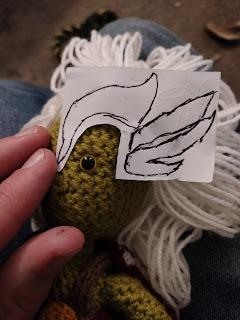 A close up of the in-progress head, with a paper template for the ears/crests